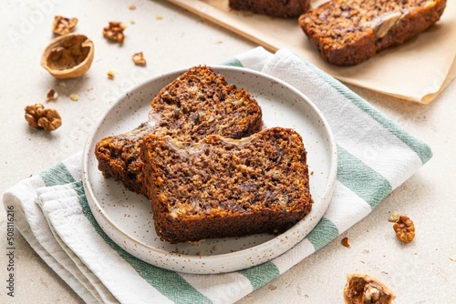 Pieces of american homemade sliced banana bread with chopped walnuts, chocolate chips and cinnamon on light background. Breakfast concept with milk. Vegan healthy food. Selective focus.