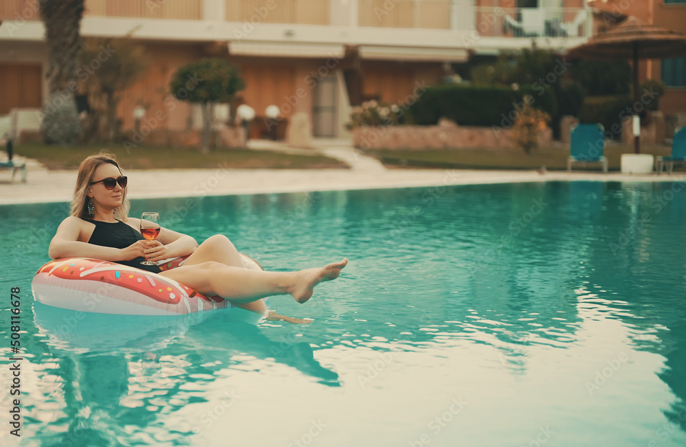 Woman with red glass of wine relaxing in swimming pool. Woman with red glass of wine relaxing in swimming pool.