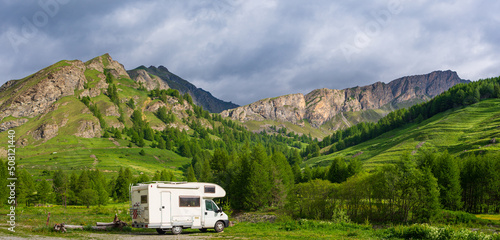 Obraz na płótnie Camper van in the mountains, the Alps, Piedmont, Italy. Sunset dramatic sky and clouds, unique highlands and rocky mountains landscape, alternative vanlife vacation concept. w salonie