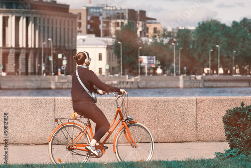 Foto A girl rides a bicycle along the embankment and listens to music