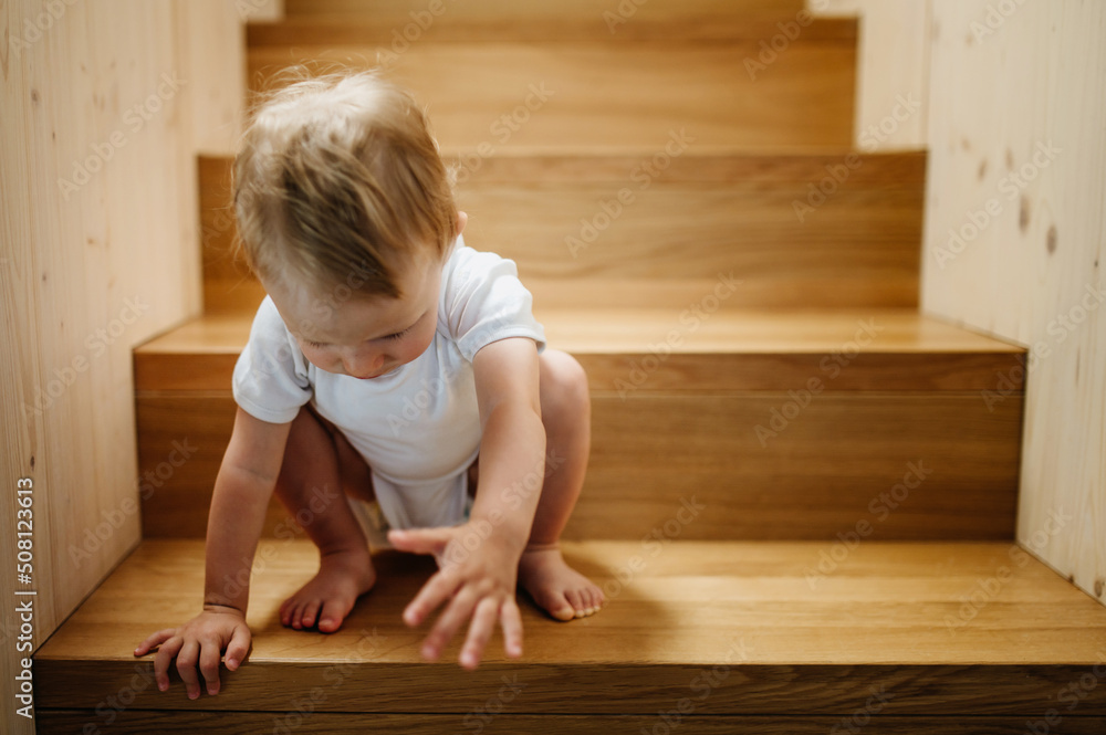 Cute little boy sitting on stairs at home and looking at camera. Cute little boy sitting on stairs at home and looking at camera.