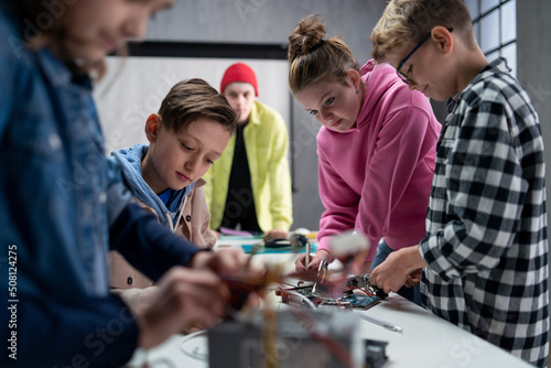 Group of kids working together on project with electric toys and robots at robotics classroom © Halfpoint