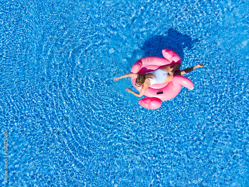 Summer holidays, enjoying summer vacations during quarantine. Aerial drone view of woman on flamingo pool float in sea.
