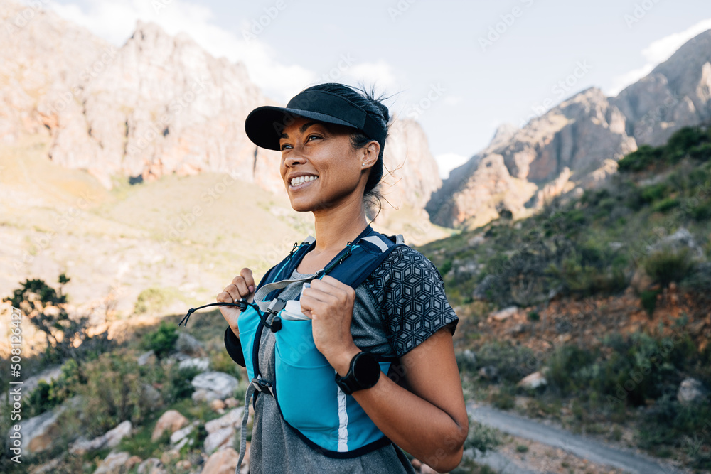 Cheerful woman in hiking attire standing outdoors looking on mountains
