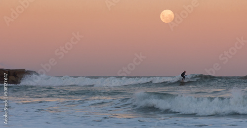 Canvas Print man surfing a wave under the full moon at sunset - Argentina