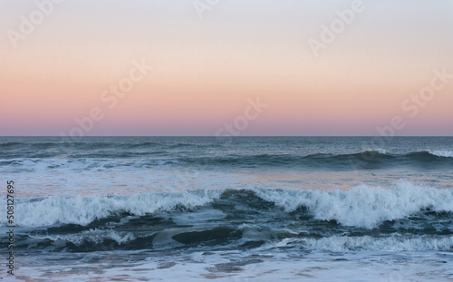 Fototapeta Naklejka Na Ścianę i Meble -  Romantic sunset with pink sky and blue waves in the sea, Walppaper