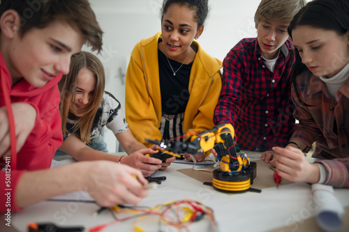 Group of students building and programming electric toys and robots at robotics classroom