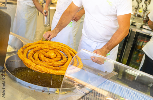 A man cooking churros in cooking oil, close up of a hands taking cooked churros out of boiling oil