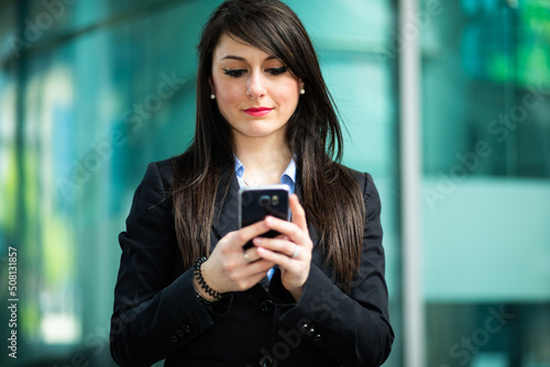Beautiful young female manager using her smartphone outdoor
