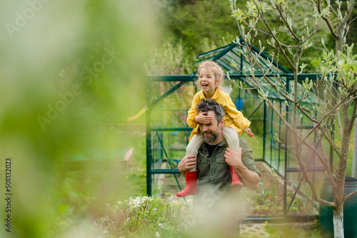 Fototapeta Naklejka Na Ścianę i Meble -  Father with his little daughter bonding in front of eco greenhouse, sustainable lifestyle.