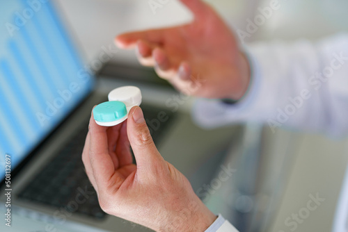 Male optometrist hands giving pair of contact lens in case to patient offering choice