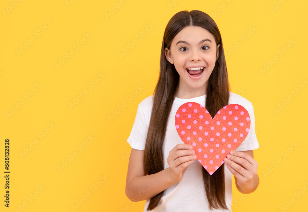 amazed teen girl holding valentines heart on yellow background, valentine day amazed teen girl holding valentines heart on yellow background, valentine day