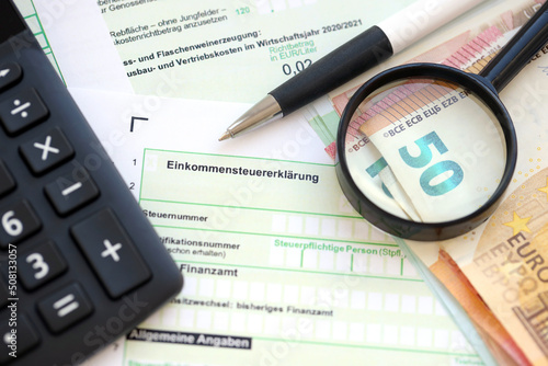 German income tax return form with pen and european euro money bills lies on accountant table close up. Taxpayers in Germany using euro currency to pay taxes photo