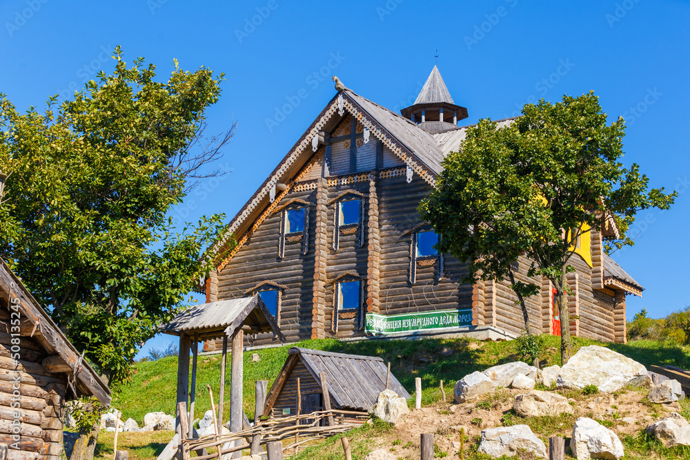 Russian wooden hut against the blue sky. Old village hut. Peasant dwelling. Stock Photo Adobe