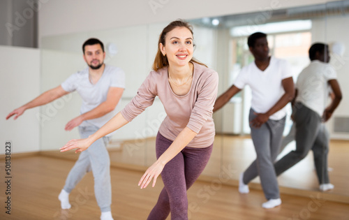 Young attractive woman visiting group choreography class, learning modern dynamic dances. Concept of active lifestyle