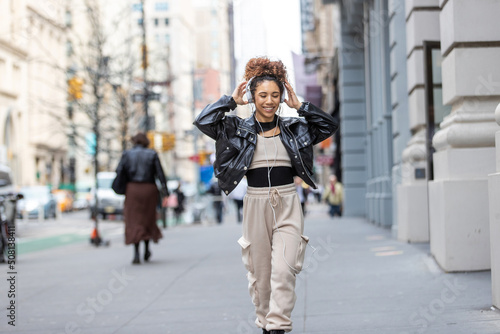African American woman wearing headphones dancing to music on city street