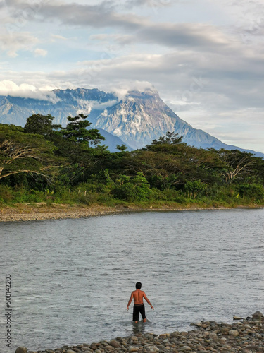 Outdoor scenery during day time with a river, forest and mount kinabalu as a background. photo