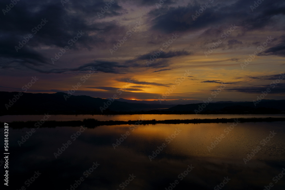 田植え前の水田の水に映り込む山里の夕景