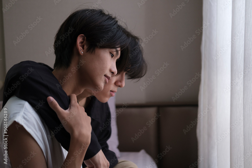 Happy gay couple sitting on bed and hugging, embracing each other while spending time together. LGBT community, equal rights, beauty and love concept. Happy gay couple sitting on bed and hugging, embracing each other while spending time together. LGBT community, equal rights, beauty and love concept.