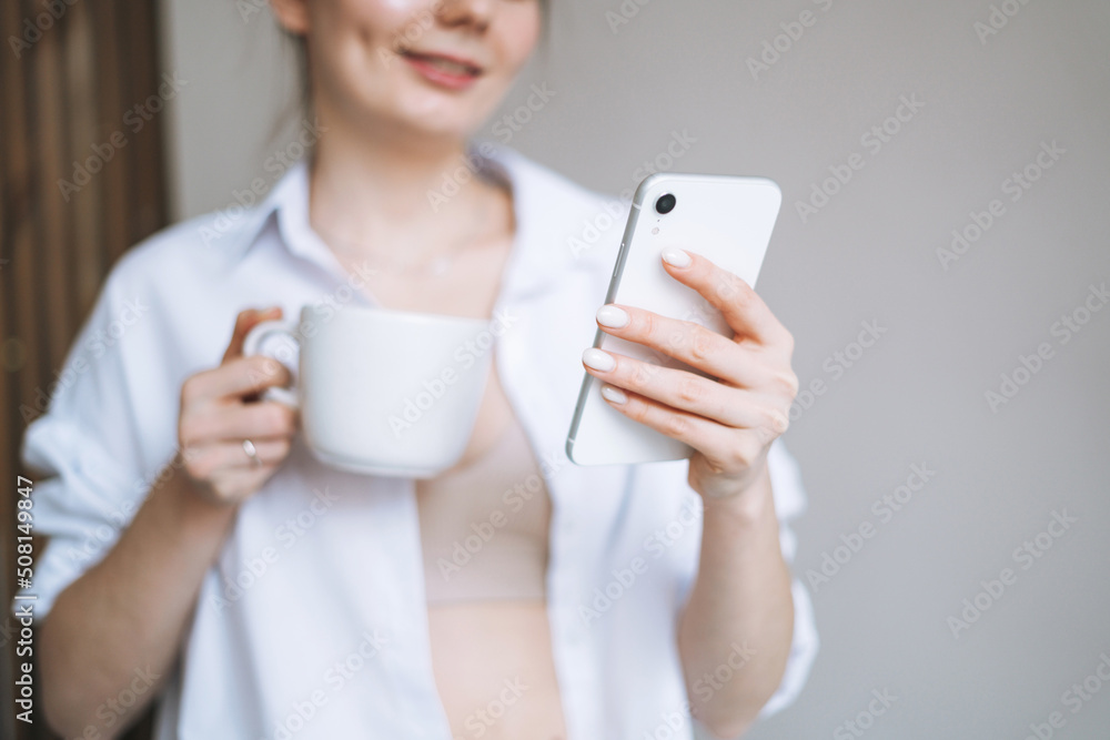 Beautiful smiling woman teenager girl student with dark long hair in casual using mobile phone in hand at the home Beautiful smiling woman teenager girl student with dark long hair in casual using mobile phone in hand at the home