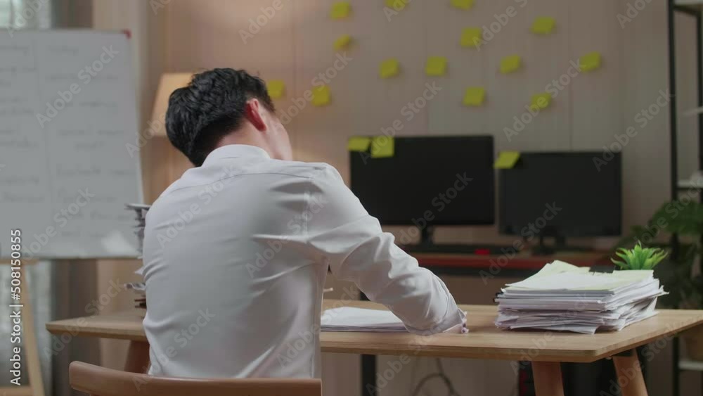 Back View Of Asian Man Yawning Before Sleeping While Working Hard With Documents At The Office
Back View Of Asian Man Yawning Before Sleeping While Working Hard With Documents At The Office