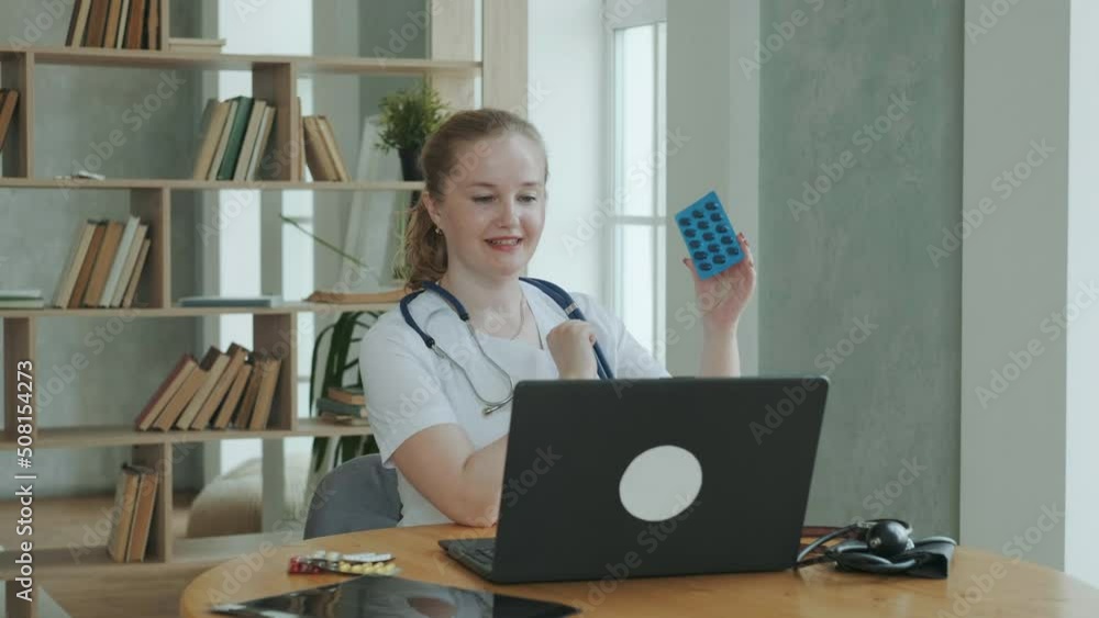 Professional doctor works at clinic. female therapist in overalls with stethoscope communicates via videoconference with patient and explains how to take prescription pills. Medical Care Online Professional doctor works at clinic. female therapist in overalls with stethoscope communicates via videoconference with patient and explains how to take prescription pills. Medical Care Online