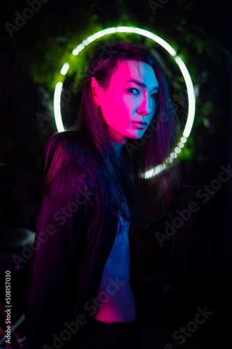 Portrait of an Asian man against the background of a circular lamp in the studio with neon light. 