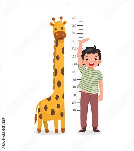 Cute Little boy measuring height of his growth on the background of wall with giraffe