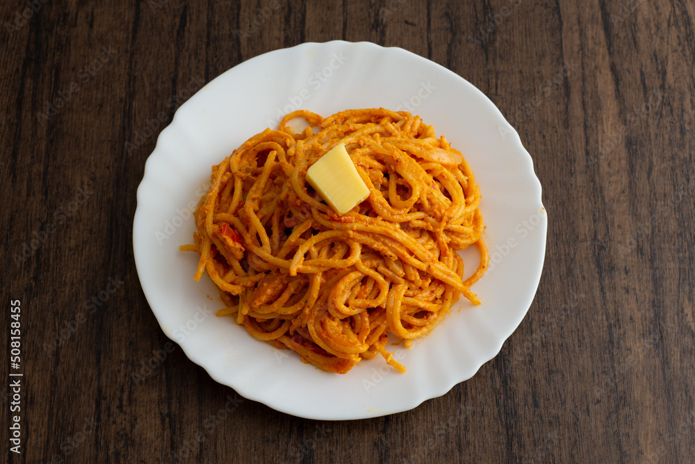Spaghetti dish served in white plate on wooden table.