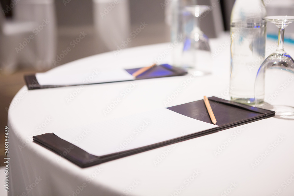 Paper, pencil, water bottle, glass on the table in the seminar room background Paper, pencil, water bottle, glass on the table in the seminar room background