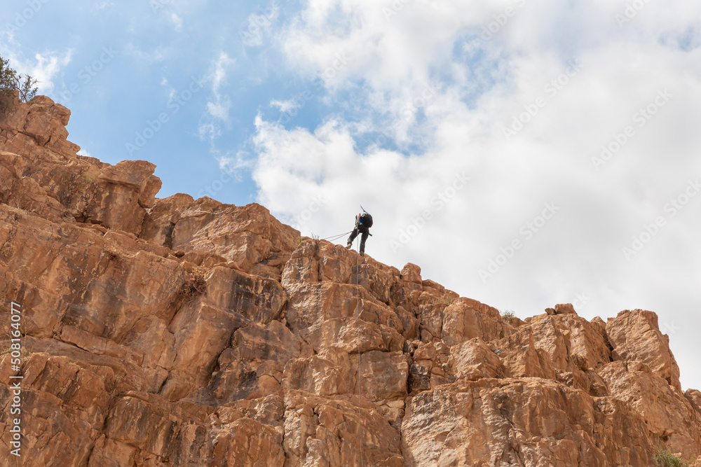 Experienced athlete on Israel Independence Day starts descending with equipment for rappel in mountains of Judean Desert, near Khatsatson stream, near Jerusalem, Israel.