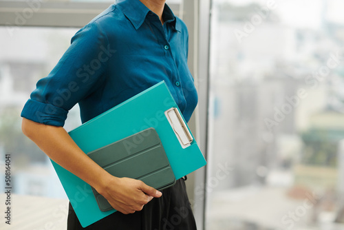 Cropped image of businesswoman carrying documants folder and digital tablet to meeting photo