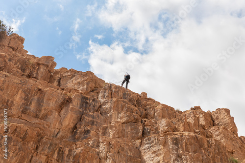 Experienced athlete on Israel Independence Day starts descending with equipment for rappel in mountains of Judean Desert, near Khatsatson stream, near Jerusalem, Israel.