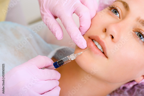 Photos Image of a young beautiful woman dressed as a patient, lying on a couch in a cosmetology clinic