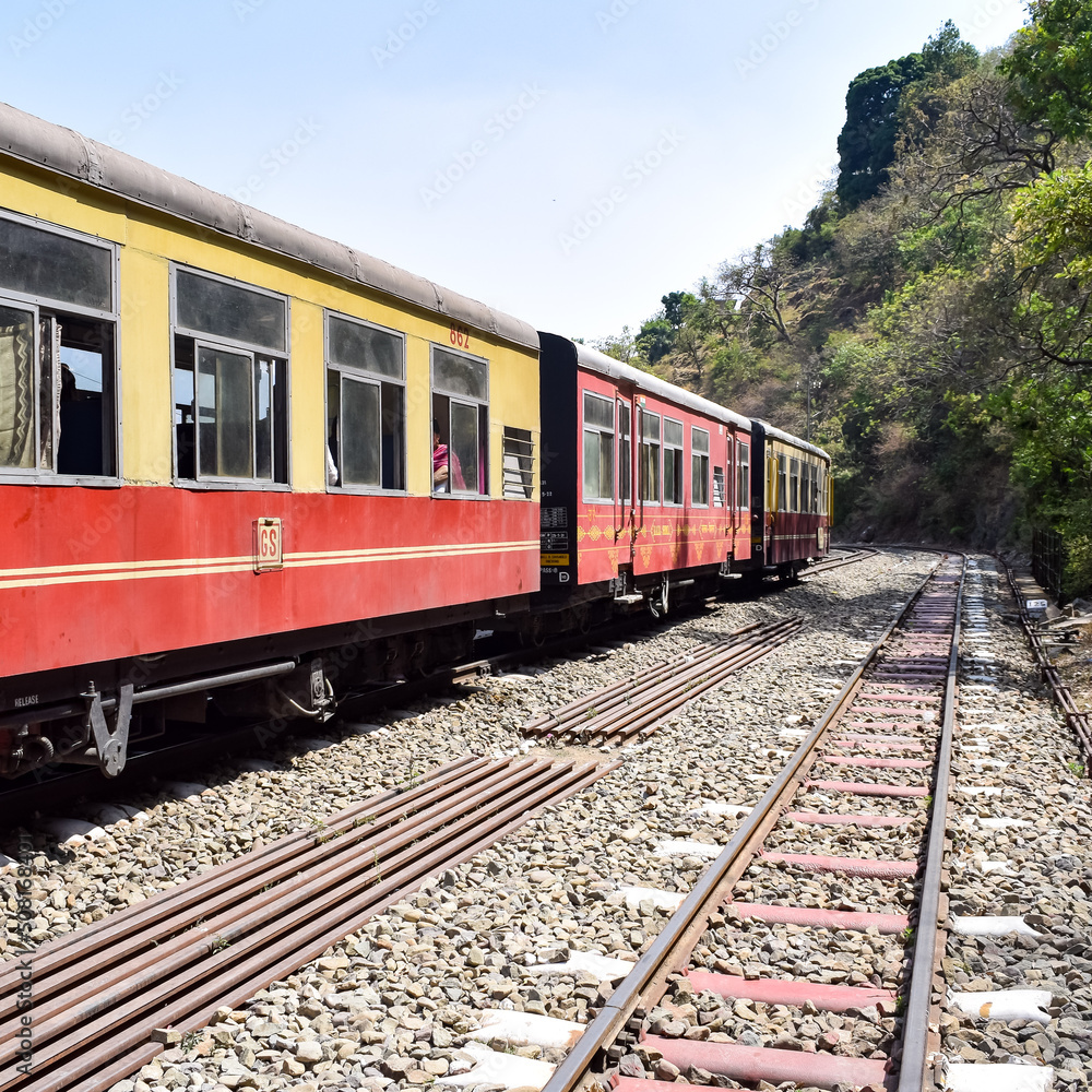 Toy Train moving on mountain slopes, beautiful view, one side mountain, one side valley moving on railway to the hill, among green natural forest. Toy train from Kalka to Shimla in India Toy Train moving on mountain slopes, beautiful view, one side mountain, one side valley moving on railway to the hill, among green natural forest. Toy train from Kalka to Shimla in India