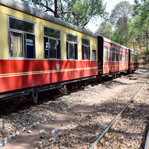 Toy Train moving on mountain slopes, beautiful view, one side mountain, one side valley moving on railway to the hill, among green natural forest. Toy train from Kalka to Shimla in India