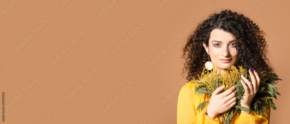 Young woman with beautiful curly hair and mimosa flowers on brown background with space for text Young woman with beautiful curly hair and mimosa flowers on brown background with space for text
