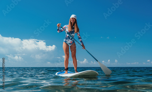 Healthy happy fit woman in bikini relaxing on a sup surfboard, floating on the clear turquoise sea water. Recreational Sports. Stand Up Paddle boarding. Summer fun, holidays travel. Active lifestyle photo