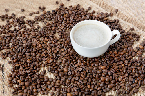 Brewed coffee in a cup against the background of coffee beans