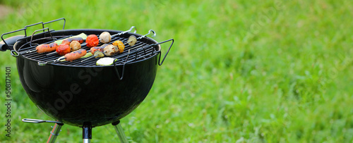 Fotografija Barbecue grill with tasty sausages and vegetables outdoors