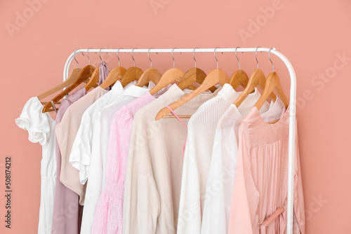 Rack with stylish female clothes near pink wall