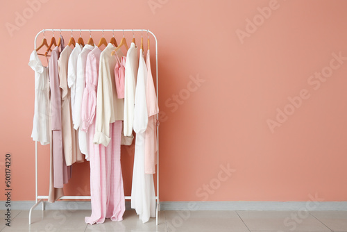Rack with stylish female clothes near pink wall © Pixel-Shot