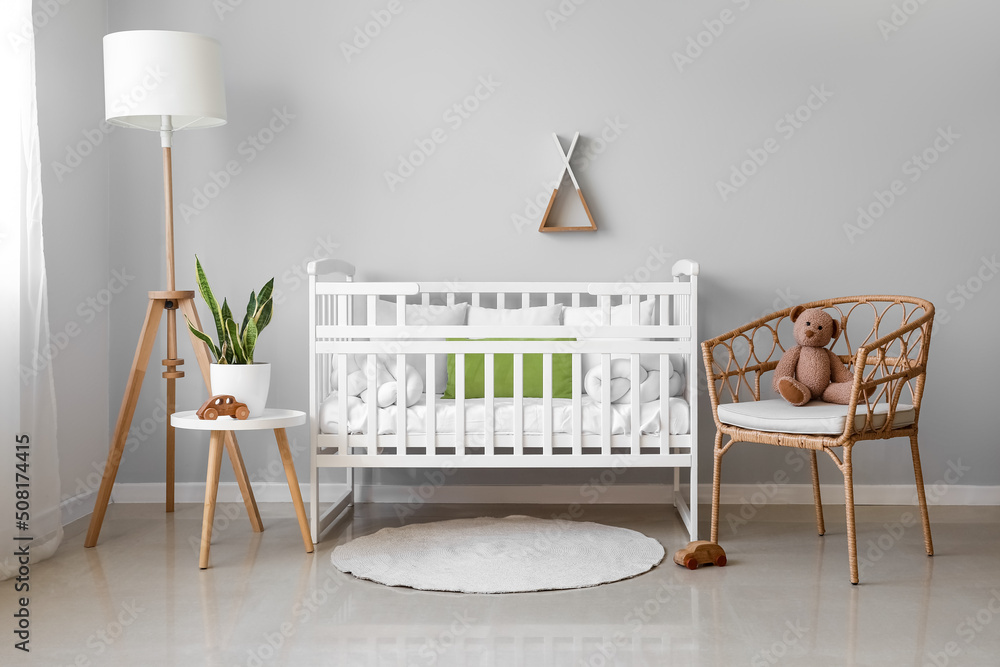 Interior of light nursery with baby crib, lamp, table and armchair - obrazy, fototapety, plakaty 