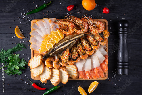 assorted fish cuts, shrimp, bread. on a black wooden background