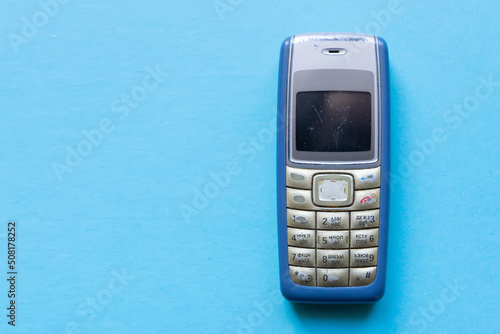 Old blue button mobile phone on blue background photo