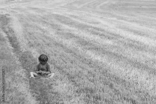 Jeune enfant assise en train de bouder dans un champ photo