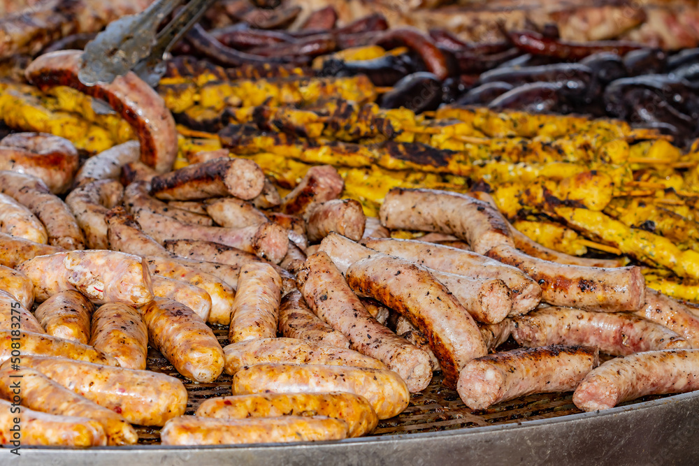 Varied meat grill, with pork, chicken skewers, sausages and chorizos, selective focus on the sausage at the bottom right of the image. Varied meat grill, with pork, chicken skewers, sausages and chorizos, selective focus on the sausage at the bottom right of the image.