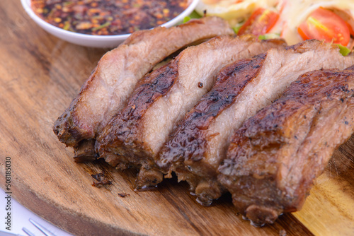 Roasted pork steak on the wooden plate with thai sauce.