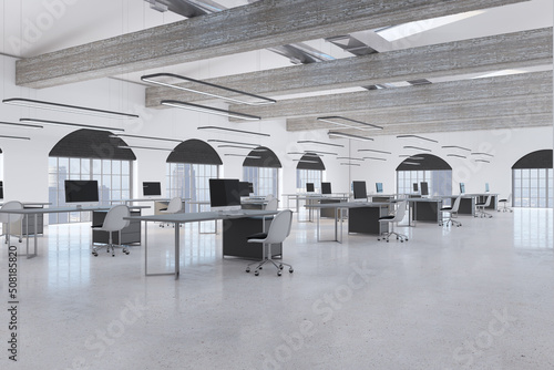 Modern coworking office interior with empty computer screens on desks  concrete flooring and window with city view. Workplace concept. 3D Rendering.