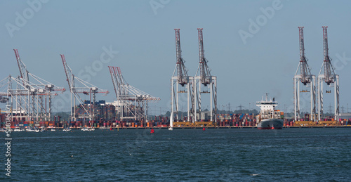 Southampton, England, UK. 2022. View of cranes and shipping at DP World container terminal and a small container ship the BF Fortaleza departing. Southampton Water, UK.